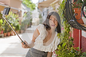 Asian girl taking self portrait on the street - young happy and attractive Asian Chinese woman visiting Seville in Spain taking