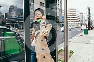 Asian girl talking on public payphone outdoors