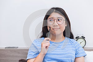 Asian girl teen nerd glasses thinking homework at home indoor