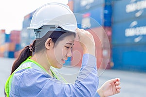Asian girl teen worker in shipping cargo port work and manage import export goods containers safety with white helmet
