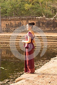 Asian Girl in Traditional Dress Sits by a Pool of Water in Angko