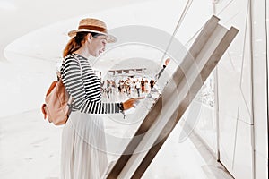 girl uses touchscreen terminal to find the right boutique in a big shopping Mall