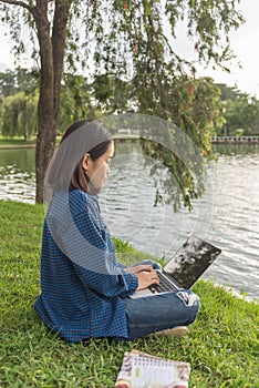 Asian girl using laptop and sitting on grass