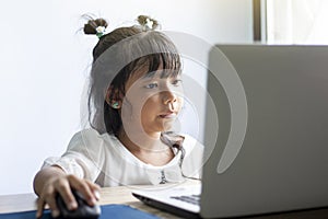 Asian girl is using laptops computers to study online at home.