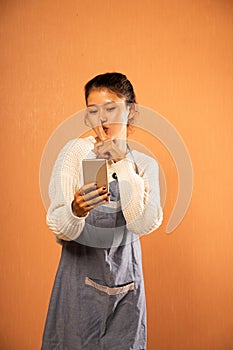 Asian girl using phone with gesture telling to be quiet
