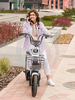 asian girl using phone while sitting on electric scooter photo