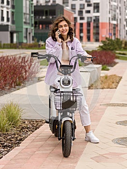 asian girl using phone while sitting on electric scooter photo