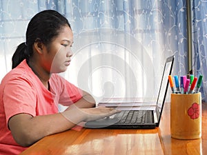 An Asian girl is watching a computer screen to learn online on a notebook. Learning from home concepts.