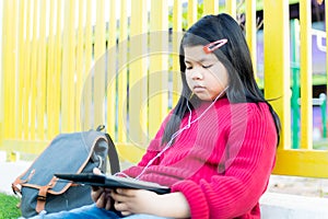 Asian girl watching a table on the school lawn