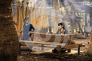 Asian girl is weaving the mat. Girl weaving mats in the countryside. Nong Khai, Thailand