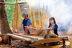 Asian girl is weaving the mat. Girl weaving mats in the countryside. Nong Khai, Thailand. My sister and sister are weaving mats