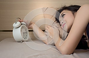 Asian girl on white bed wake up late look at alarm clock