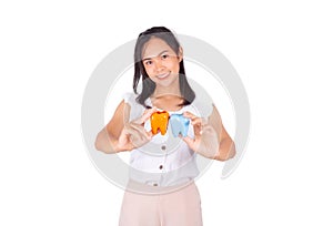 An Asian girl in white tank top and baige trunk holds ceramic tooth in her hands