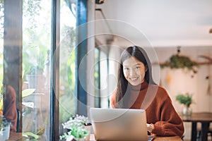 Asian girl working at a coffee shop with a laptop