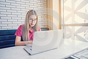 Asian girl working at a coffee shop sitting with mobile phone an