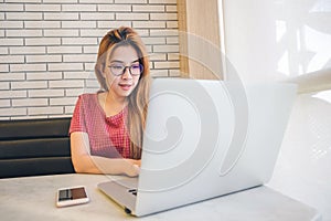 Asian girl working at a coffee shop sitting with mobile phone an