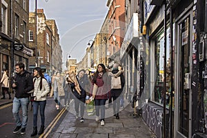 Asian girls with bouquets of flowers walk along Brick Lane