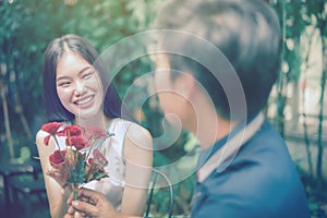 Asian girls are delighted with the red flowers received from the man she loved.