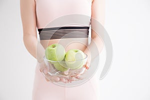 Asian girls holding a glass bowl with apples on white background