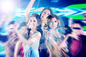 Asian girls partying on dance floor of disco nightclub