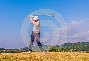 Asian golfer hitting golf ball on green fairway