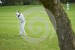 Asian golfer swinging club for a stroke in golf course