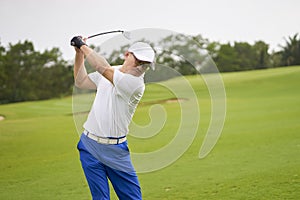 Asian man swinging club for tee-off in course