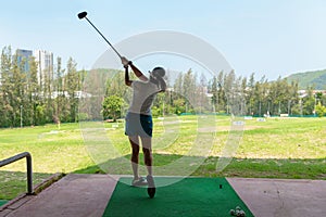 Asian golfer woman swing golf ball practice at golf driving range on evening on time for healthy sport.