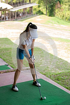 Asian golfer woman swing golf ball practice at golf driving range for relax and healthy care port