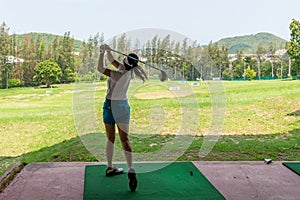 Asian golfer woman swing golf ball practice at golf driving range for relax and healthy care port.