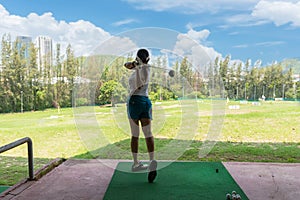 Asian golfer woman swing golf ball practice at golf driving range for relax and healthy care sport.