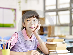 Asian grade school student thinking in classroom