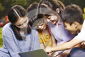 Asian grade school students using laptop together