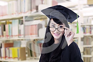 Asian graduate in graduation gown pose at library