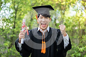 Asian Graduate man put hands up and celebrating with certificate in her hand and so proud and happiness in Commencement day,