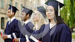 Asian graduate student with diploma, smiling into camera, international studies