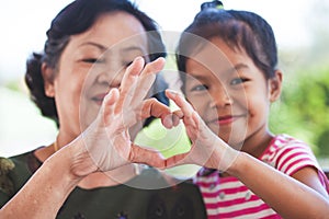 Asian grandmother and little child girl making heart shape with hands together photo