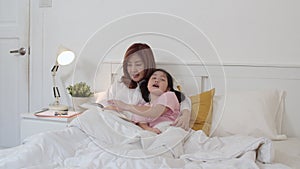 Asian grandmother read fairy tales to granddaughter at home. Senior Chinese, grandma happy relax with young girl enjoy good