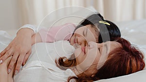 Asian grandmother sleep at home. Senior Chinese, grandma happy relax with young granddaughter girl kissing cheek for waking up