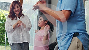 Asian grandparents and granddaughter listen to music and dance together at home. Senior Chinese, grandpa and grandma happy spend