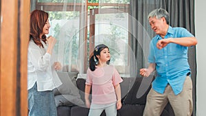 Asian grandparents and granddaughter listen to music and dance together at home. Senior Chinese, grandpa and grandma happy spend