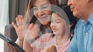 Asian grandparents and granddaughter video call at home. Senior Chinese, grandpa and grandma happy with girl using mobile phone