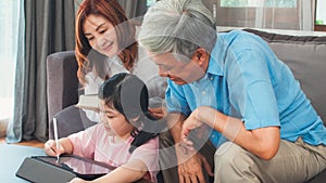 Asian grandparents and granddaughter video call at home. Senior Chinese, grandpa and grandma happy with girl using mobile phone