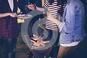 Asian group of friends having outdoor garden barbecue laughing w