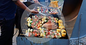 Asian group of friends having outdoor garden barbecue laughing with alcoholic beer drinks on night