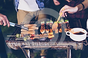 Asian group of friends having outdoor garden barbecue laughing w