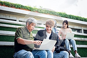 Asian group student, old age and young sitting on the stairs, they are looking and happiness to review the lesson