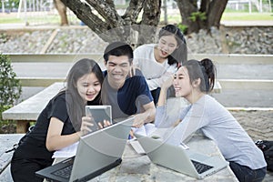 Asian Group of students using tablet and notebook sharing with t