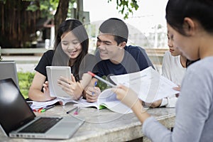 Asian Group of students using tablet and notebook sharing with t