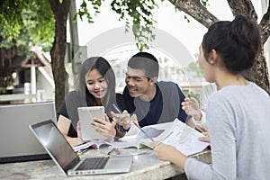 Asian Group of students using tablet and notebook sharing with t